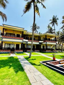 瓦尔卡拉Maadathil Beach Resort的一座棕榈树的黄色建筑
