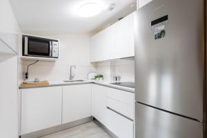 帕伦西亚INSIDEHOME Apartments - La Casita de Montse的厨房配有白色橱柜和不锈钢冰箱