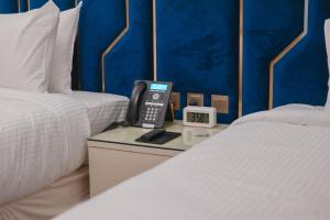 麦地那La Cordia Hotel Apartment的一间酒店客房,在两张床之间的一张桌子上配有电话