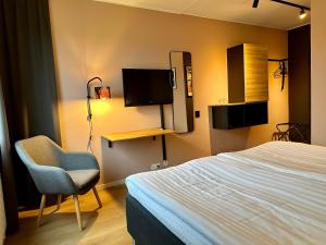 乌尔里瑟港Hotell Nyboholm的一间卧室配有一张床、一把椅子和电视。