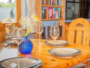 巴特阿罗尔森Holiday Home Ferienhaus Bude 87 by Interhome的一张带玻璃杯和盘子的木桌,蓝色花瓶