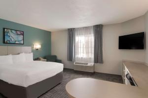 路易斯威尔MainStay Suites Louisville Jeffersontown的配有一张床和一台平面电视的酒店客房