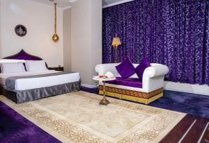 多哈萨拉亚滨海酒店 的一间卧室配有紫色窗帘、一张床和一张沙发