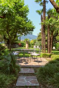 卡斯拉诺Villa Garni Gardenia的一个带桌椅和棕榈树的庭院