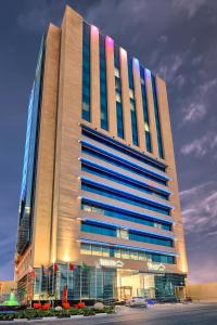多哈萨拉亚滨海酒店 的停车场内有蓝色窗户的大型高楼