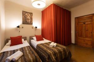 里加两轮酒店的一间卧室设有两张床和红色窗帘