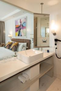 新德里阿斯坦萨诺瓦门廊酒店的白色的浴室设有水槽和一张床