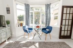 伯恩茅斯Modern flat, sleeps 4, close to beach,Parking,WiFi - Queens Park Views的一间设有玻璃桌和两把蓝色椅子的用餐室