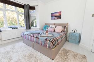 伯恩茅斯Modern flat, sleeps 4, close to beach,Parking,WiFi - Queens Park Views的一间卧室配有一张带蓝色床头柜和窗户的床。