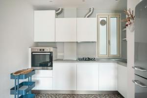 米兰Isola Milano apartment的厨房配有白色橱柜和炉灶。