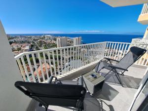 美洲海滩Panoramic Floor - Las Americas的阳台配有2把椅子、烧烤架和海洋