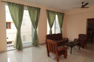 蓬蒂切里Soundar villa的客厅配有两把椅子和两扇窗户
