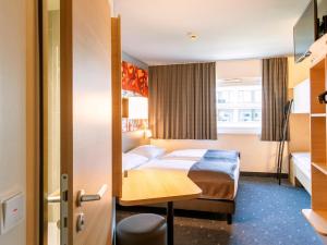 慕尼黑慕尼黑城西住宿加早餐酒店的配有一张床和一张书桌的酒店客房