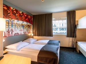 慕尼黑慕尼黑城西住宿加早餐酒店的酒店客房设有一张床,墙上挂有绘画作品