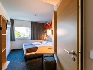 慕尼黑慕尼黑城西住宿加早餐酒店的配有一张床和一张书桌的酒店客房