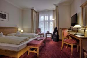埃尔丁Hotel zum ERDINGER Weißbräu的酒店客房,配有一张床、一张桌子和椅子
