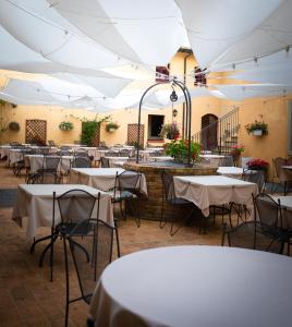 圣吉米纳诺Hotel & Restaurant Casolare Le Terre Rosse的一间摆放着桌椅和白色遮阳伞的房间