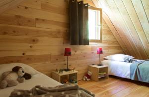 丰罗穆Huttopia Font Romeu的一间卧室设有木墙和一张带泰迪熊的床