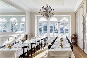 巴塞尔克拉夫特巴夏尔酒店的一间长餐厅,配有白色的桌子和椅子