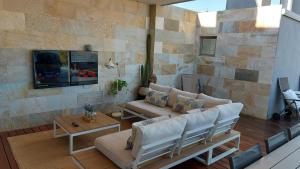 埃尔切Ático de Lujo con Jacuzzi Climatizado en Terraza的客厅配有沙发和石墙电视。