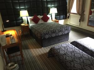 格拉斯哥列王公园酒店的酒店客房设有两张床、一张桌子和灯具。