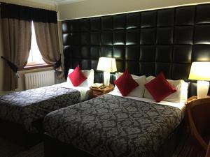格拉斯哥列王公园酒店的两张位于酒店客房的床铺,配有红色枕头