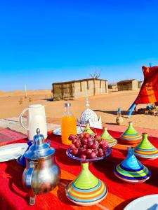 MhamidMhamid Sahara Golden Dunes Camp - Chant Du Sable的桌上放有盘子和果盘的桌子