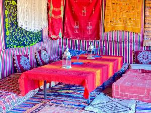 MhamidMhamid Sahara Golden Dunes Camp - Chant Du Sable的一间设有一张桌子的房间,配有红色桌布