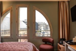 巴黎Royal Garden Champs-Élysées的一间卧室设有三扇窗户、一张粉红色的床和椅子
