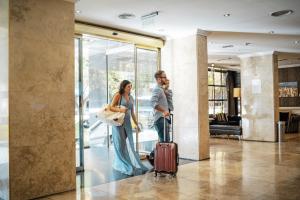 科尔多瓦阿梅里安科尔多瓦公园酒店 的大堂里一个男人和一个女人拿着手提箱