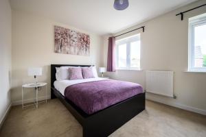 KillingbeckWykebeck Mount by Our Home Short Stays的一间卧室配有一张带紫色毯子的床和两个窗户。
