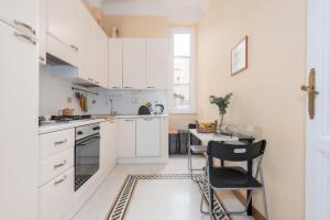 罗马TRASTEVERE APARTMENT - ZEN REAL ESTATE SRL的厨房配有白色橱柜和桌椅