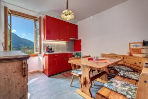 CastasegnaIn val Bregaglia mille possibilità di benessere的厨房配有红色橱柜和木桌