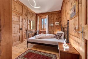 CastasegnaIn val Bregaglia mille possibilità di benessere的卧室配有一张床铺,位于带木墙的房间内