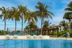 普拉亚卡门MAREAZUL Beachfront Apartment 2BR Private Pool Casa Áncora的一个带椅子的游泳池,棕榈树