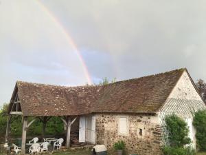 Petit Moulin Renaisance的石屋上方的彩虹,配有桌椅
