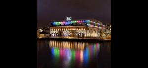 都柏林Modern Dublin City Centre的一座在水面上夜亮着五颜六色灯光的建筑