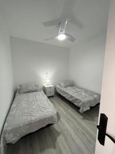 米哈斯Ataraxia Casa Vacacional的一间卧室配有两张床和一个带灯的床头柜