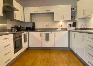 纽约Amazing 2 Bedroom Apartment At UES的厨房铺有木地板,配有白色橱柜。