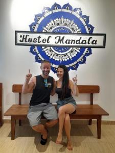 安君纳Hostel Mandala的坐在凳子上,在标志下的一个男人和女人