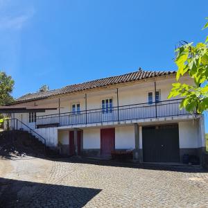 布拉干萨Casa de Cabecinho- Albufeira do Azibo的白色的建筑,设有红色的门和阳台