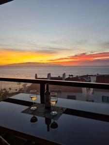 圣地亚哥港Bahia de Santiago的两杯葡萄酒坐在桌子上,享有海景