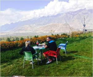 锡卡都Hotel Mountain Lodge Skardu的坐在草桌旁的男人和女人