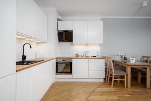 华沙Apartments 24h的厨房配有白色橱柜和木桌