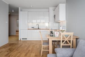 华沙Apartments 24h的厨房配有白色橱柜和桌椅
