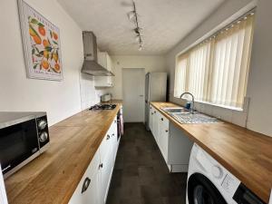 米德尔斯伯勒4 bed 3 bedroom home near Middlesbrough centre的厨房配有白色橱柜和木制台面