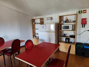 布拉加Guest House Sir Manuel - Unidade São Vicente的厨房配有红色的桌椅和冰箱。