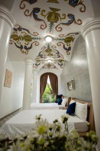 顺化HELLO VILLA & SPA的一间卧室设有两张床,天花板上装饰有绘画作品
