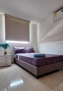 内瓦CB Apto cómodo e impecable con Aire Acondicionado的一间卧室配有一张带紫色枕头的床