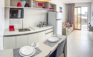 雅克南FLATS ENSEADA Do SOL的厨房配有白色橱柜和一张桌子,上面有两个盘子